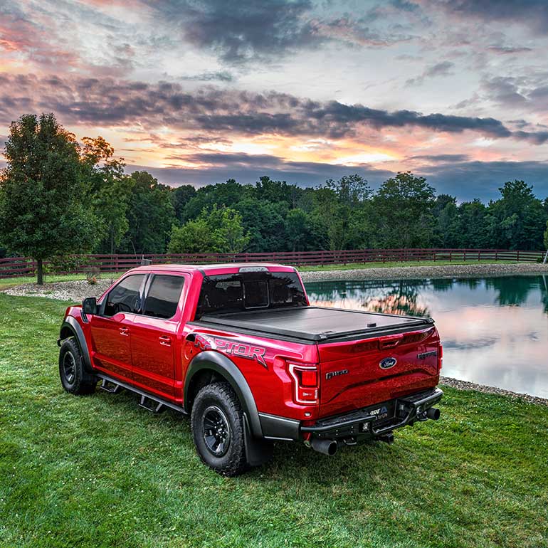 Side view of a red truck by a lake 